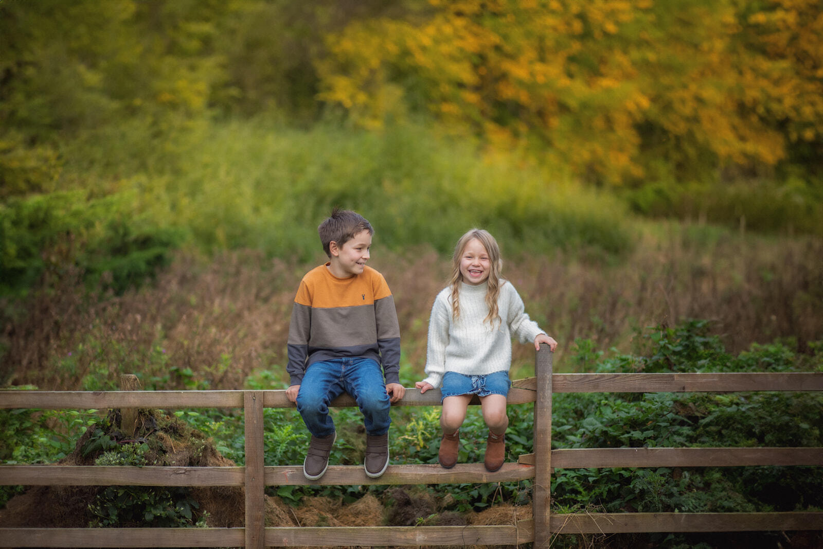 Siblings | Lifestyle Photo Brother and sister seating on a fence in their garden in Lincolnshrie
